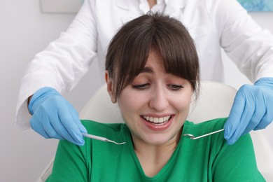 Scared woman having appointment with dentist on grey background