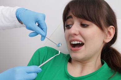 Photo of Scared woman having appointment with dentist on grey background