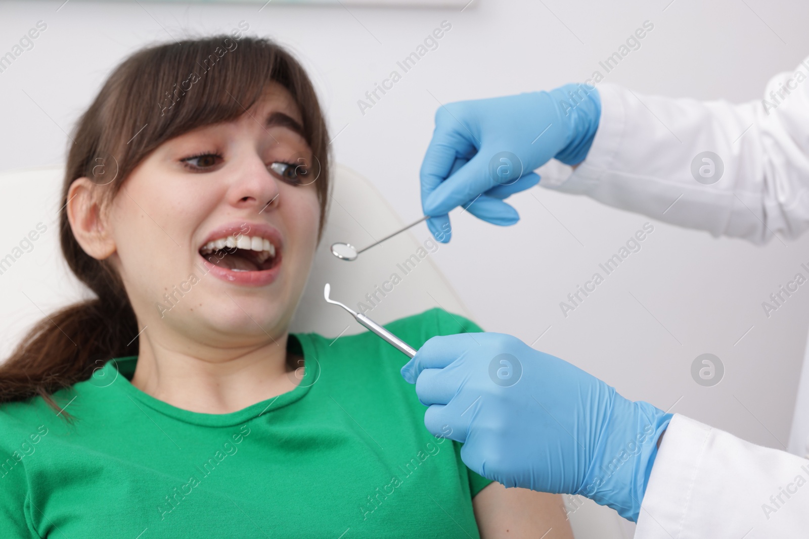 Photo of Scared woman having appointment with dentist on grey background