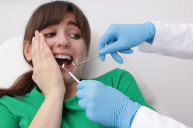 Scared woman having appointment with dentist on grey background, selective focus