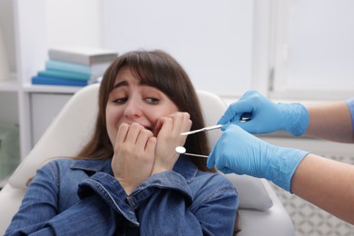 Photo of Scared woman having appointment with dentist in clinic