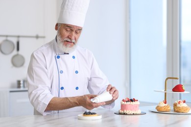 Elderly pastry chef making dessert at table in kitchen