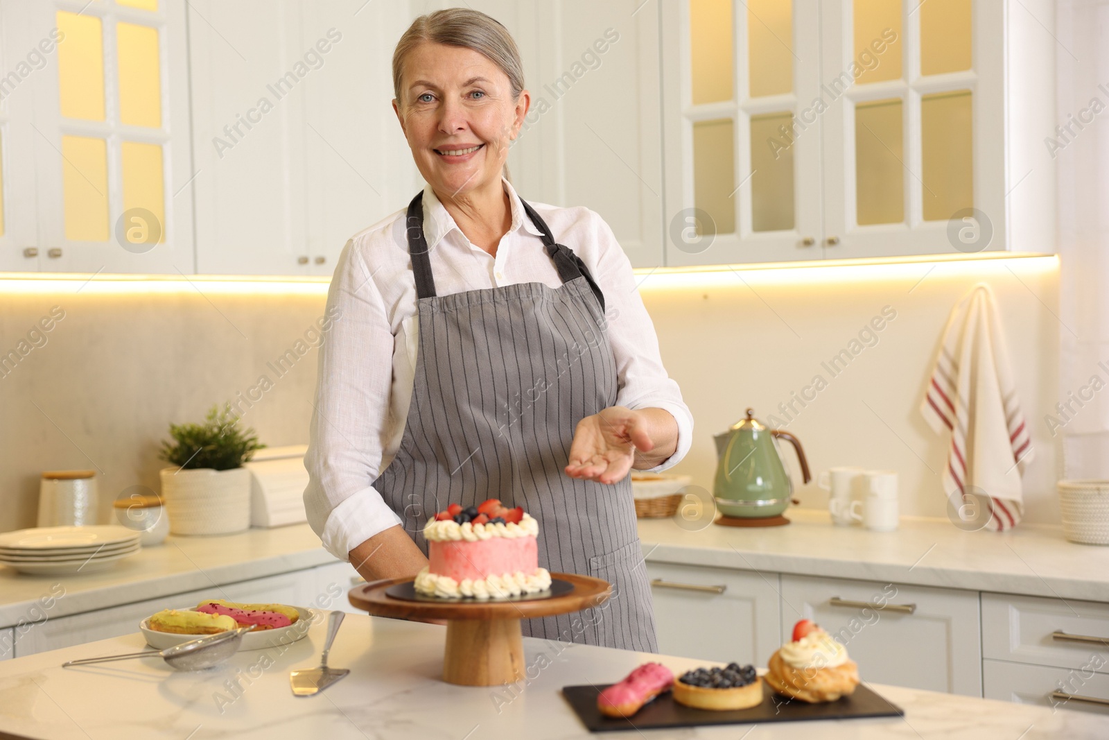 Photo of Smiling pastry chef at table with desserts in kitchen