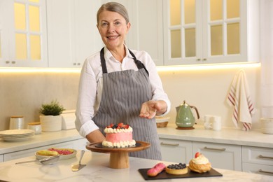 Photo of Smiling pastry chef at table with desserts in kitchen