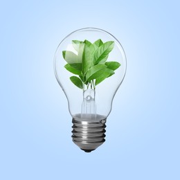 Light bulb with fresh leaves inside in air on light blue background. Concepts of eco-friendly environment and saving energy