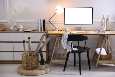 Image of Comfortable workplace at home. Computer monitor with blank white screen on desk in room