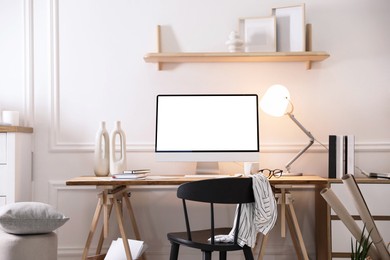 Comfortable workplace at home. Computer monitor with blank white screen on desk in room