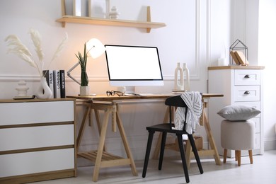 Comfortable workplace at home. Computer monitor with blank white screen on desk in room