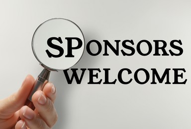 Image of Sponsors Welcome. Woman looking at text through magnifying glass on white background, closeup