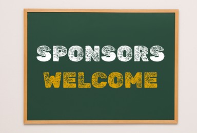 Image of Green chalkboard with text Sponsors Welcome hanging on grey wall