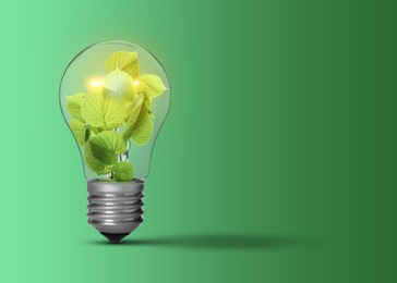 Image of Light bulb with fresh leaves inside on green background, space for text. Concepts of eco-friendly environment and saving energy