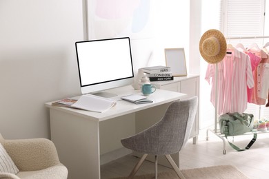 Comfortable workplace at home. Computer monitor with blank white screen on desk in room