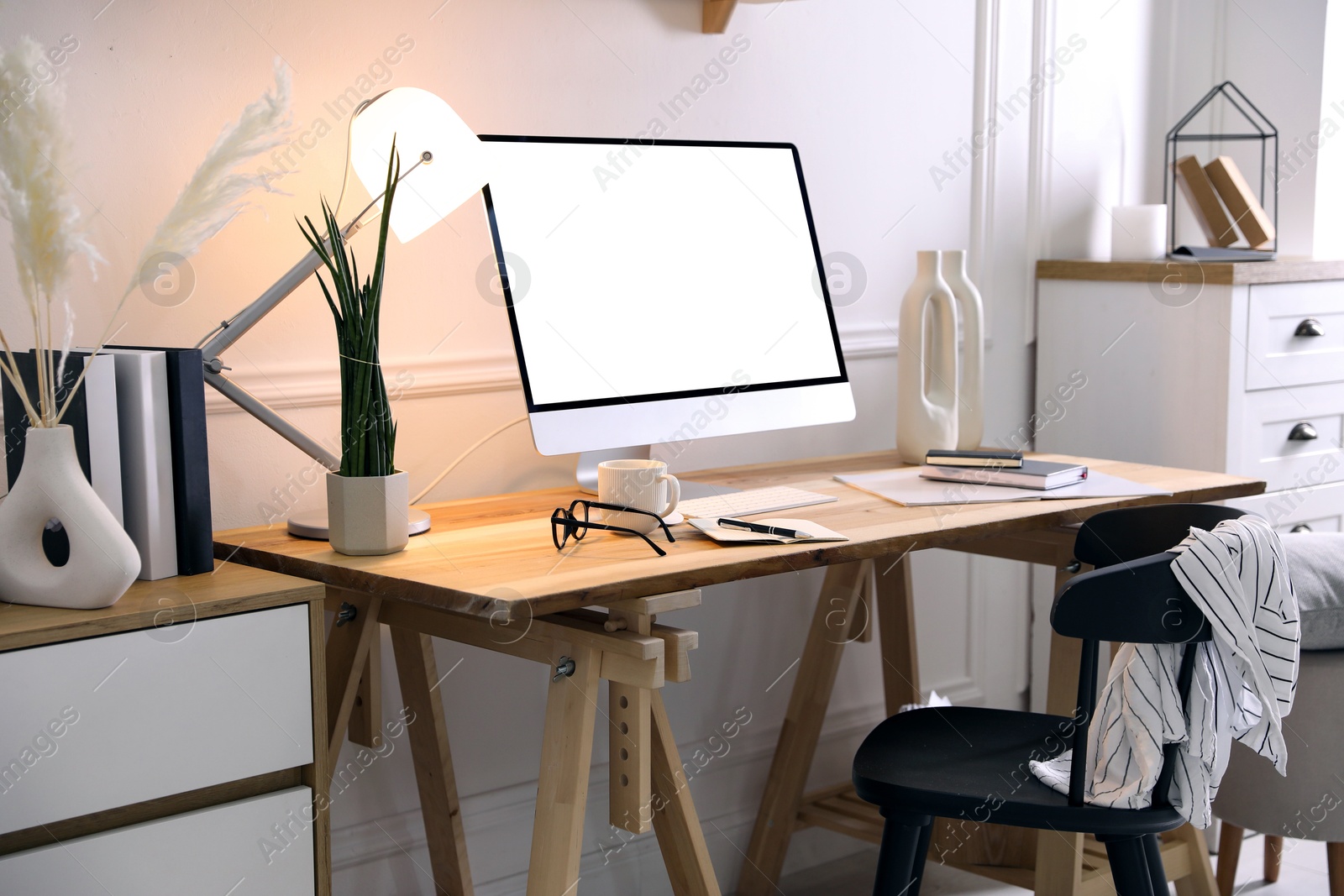 Image of Comfortable workplace at home. Computer monitor with blank white screen on desk in room