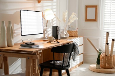 Image of Comfortable workplace at home. Computer monitor with blank white screen on desk in room