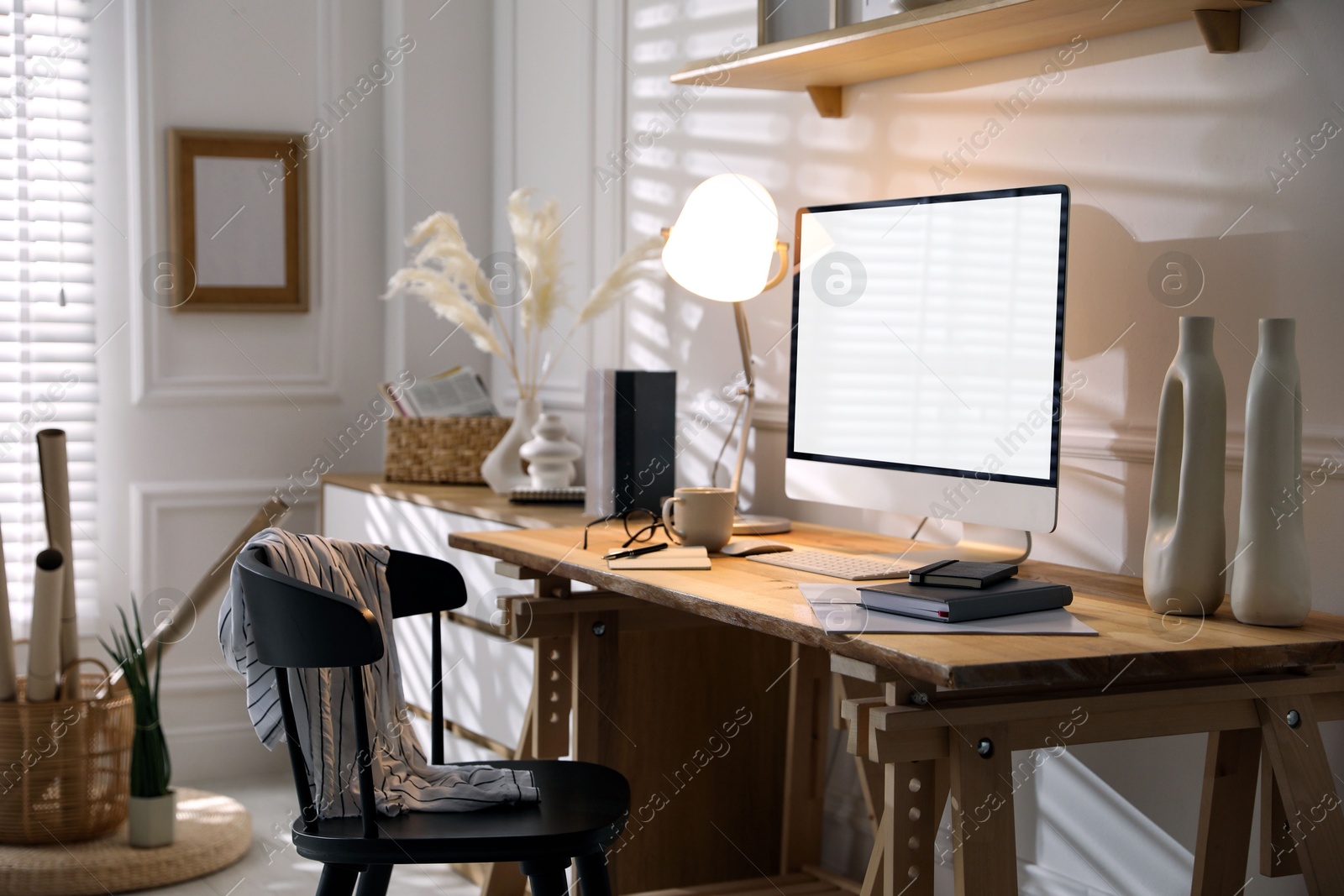 Image of Comfortable workplace at home. Computer monitor with blank white screen on desk in room