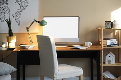 Comfortable workplace at home. Computer monitor with blank white screen on desk in room