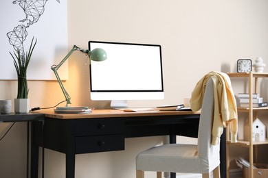 Comfortable workplace at home. Computer monitor with blank white screen on desk in room