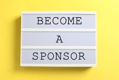 Letter board with text Become A Sponsor on yellow background