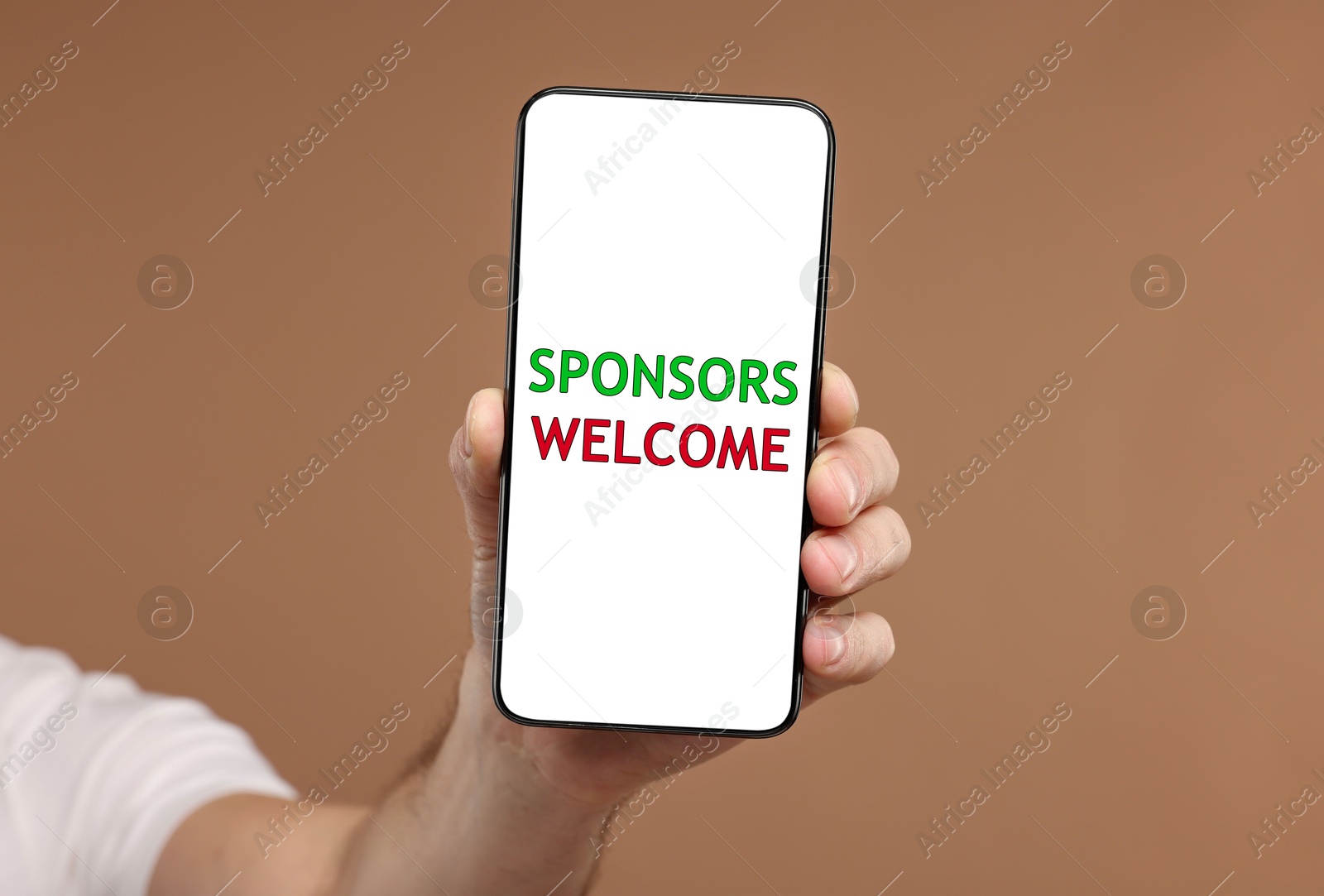 Image of Man showing smartphone with text Sponsors Welcome on screen against pale brown background, closeup