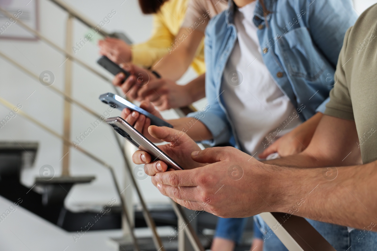 Photo of Internet addiction. Group of people with smartphones on stairs indoors, closeup