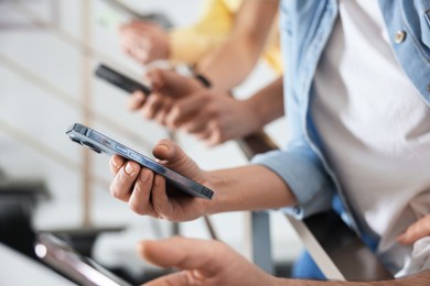 Photo of Internet addiction. Group of people with smartphones on stairs indoors, closeup