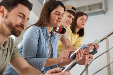 Internet addiction. Group of people with smartphones on stairs indoors