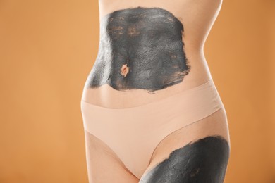 Photo of Woman doing spa body wraps on beige background, closeup