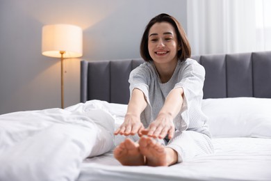 Photo of Young woman exercising on bed at home. Morning routine