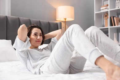 Photo of Young woman exercising on bed at home. Morning routine