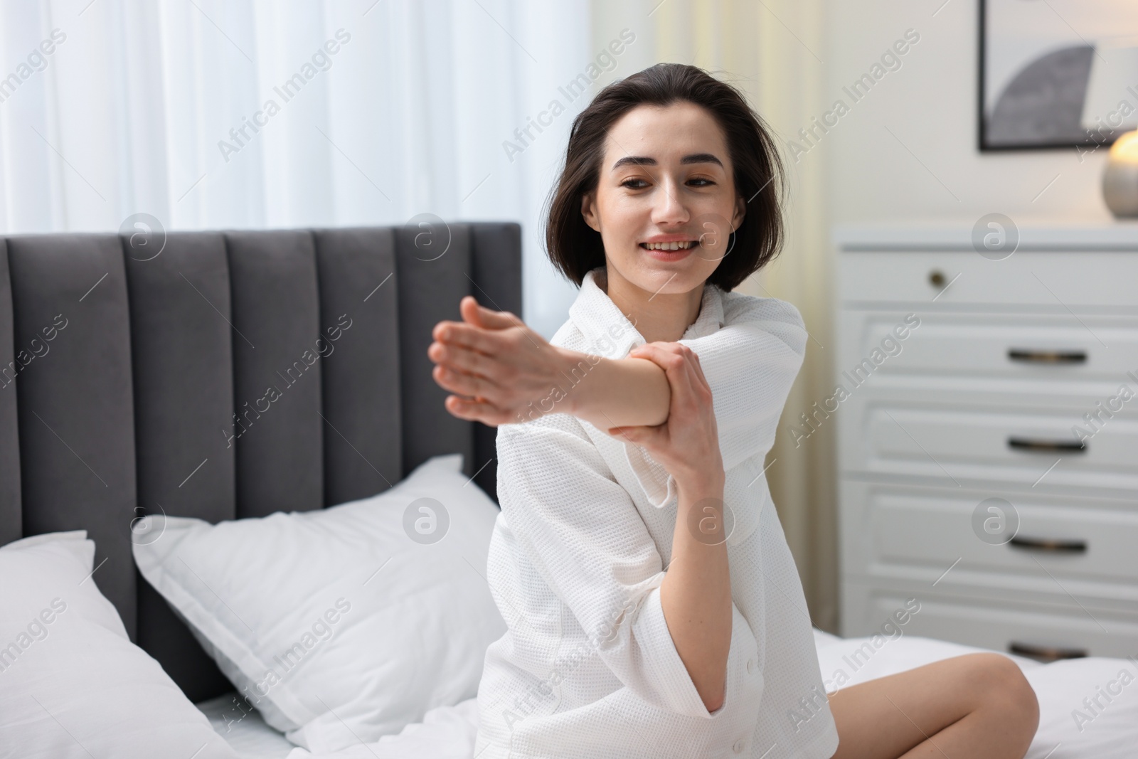 Photo of Young woman exercising on bed at home. Morning routine