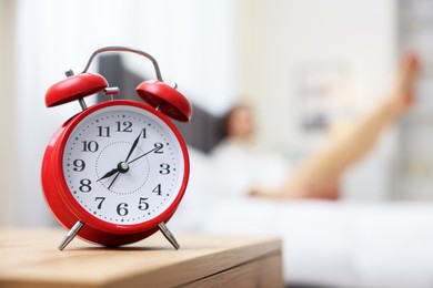 Young woman exercising on bed at home, focus on alarm clock. Morning routine