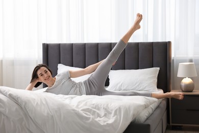 Young woman exercising on bed at home. Morning routine