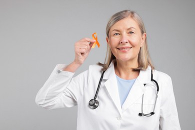 Multiple Sclerosis awareness. Doctor with orange ribbon on light grey background