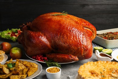 Whole baked turkey and other dishes served on grey table, closeup