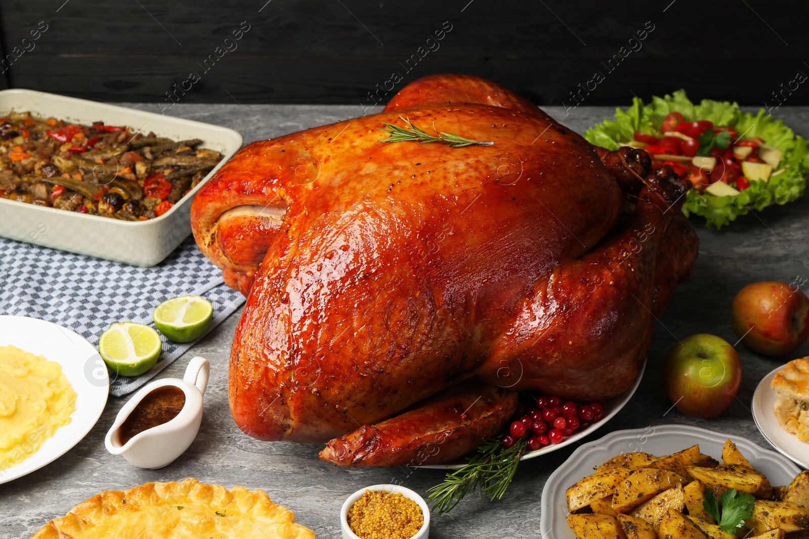 Photo of Whole baked turkey and other dishes served on grey table, closeup