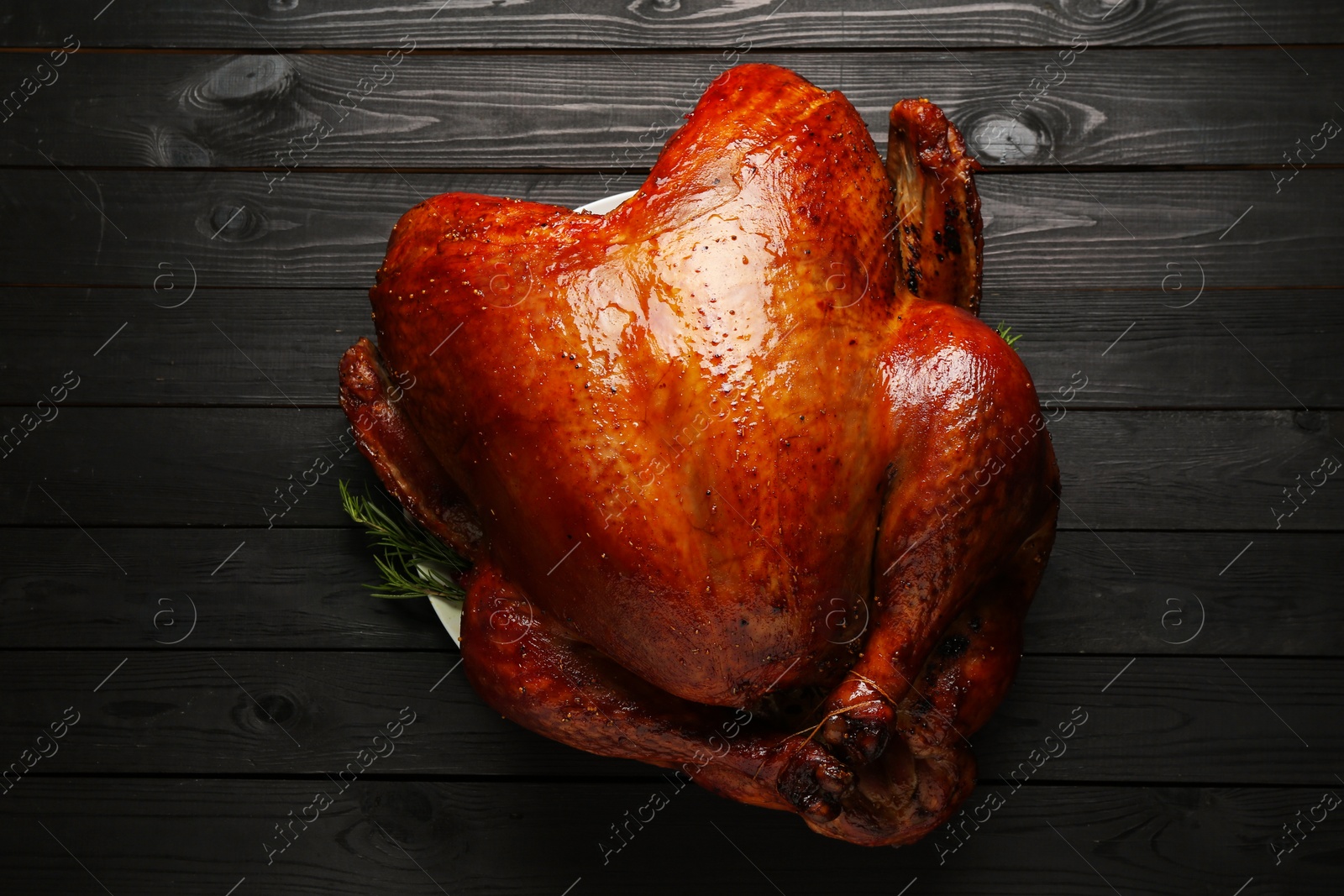 Photo of Whole baked turkey on black wooden table, top view