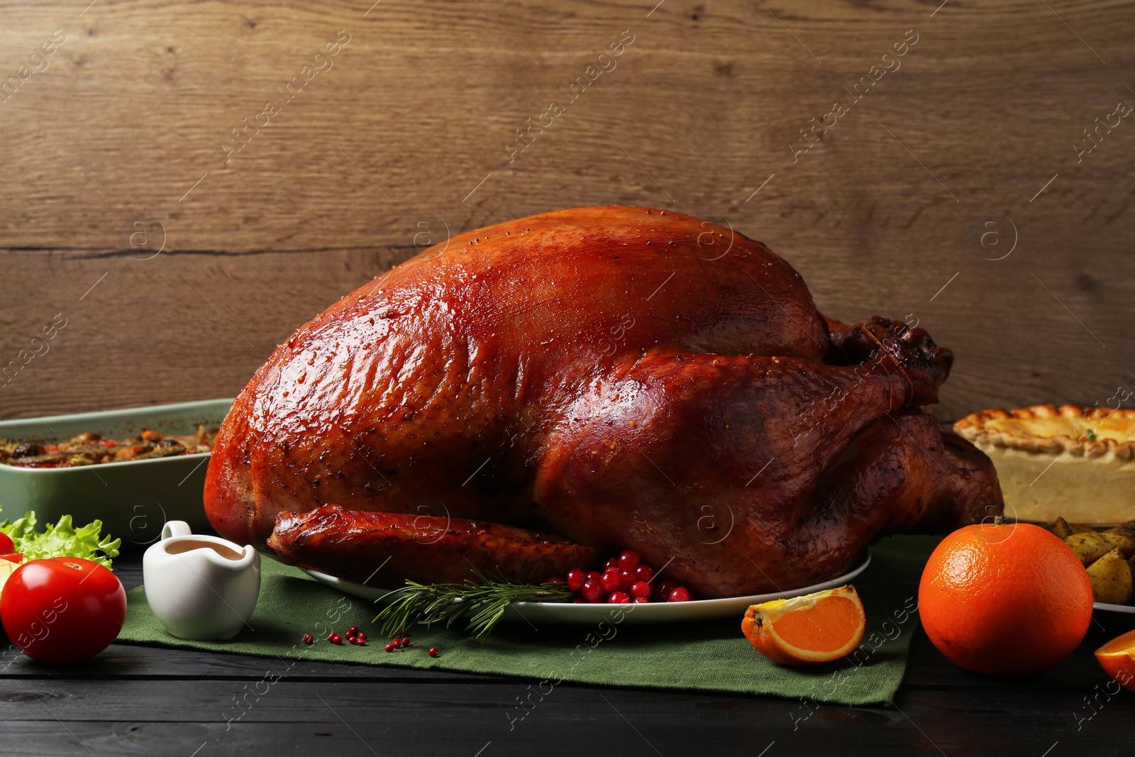 Photo of Whole baked turkey and other dishes served on black wooden table