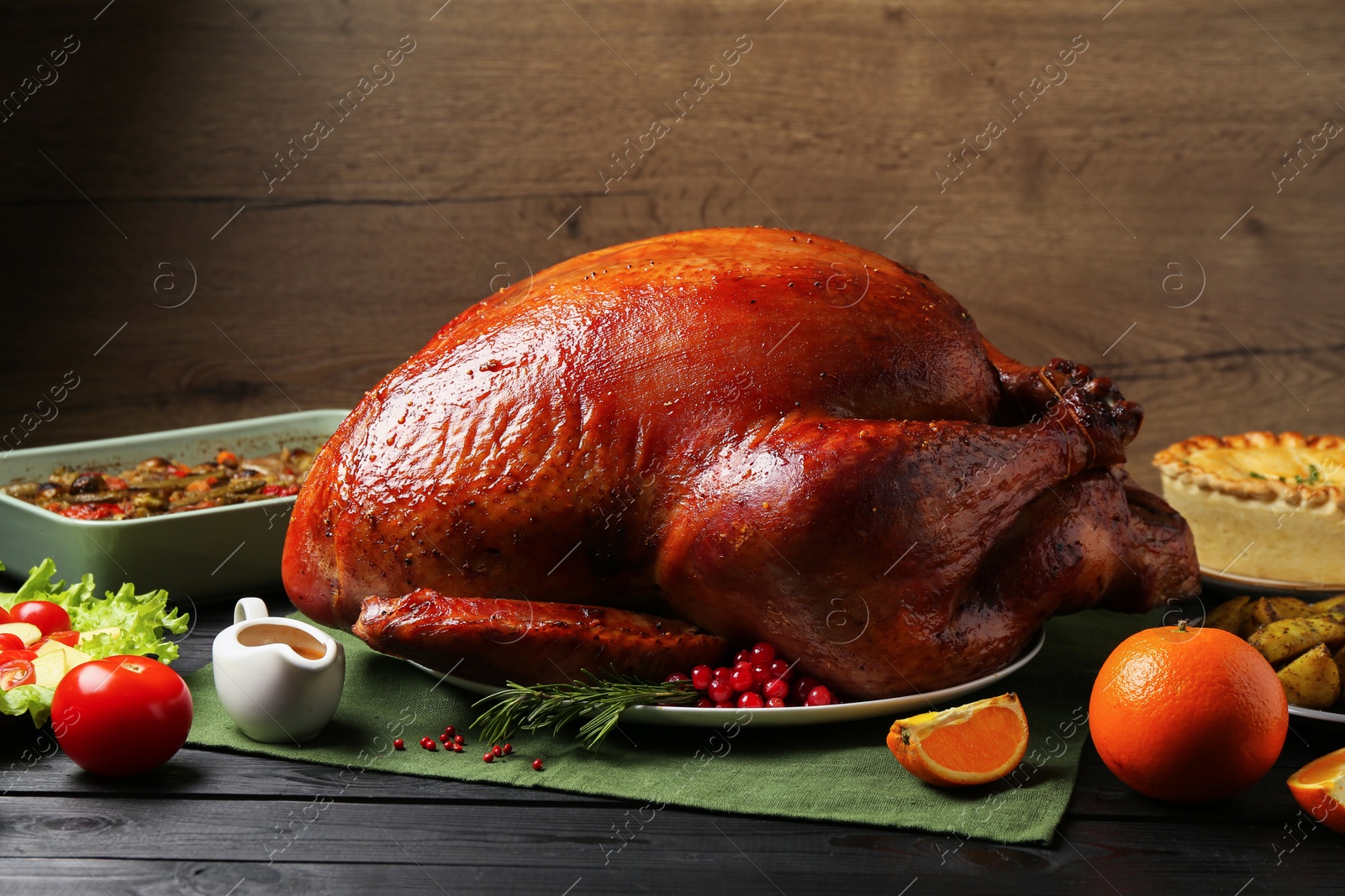 Photo of Whole baked turkey and other dishes served on black wooden table