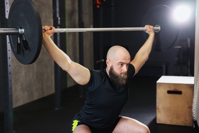 Photo of Sportsman with barbell during crossfit workout in gym