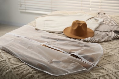 Photo of Garment cover with clothes on bed indoors