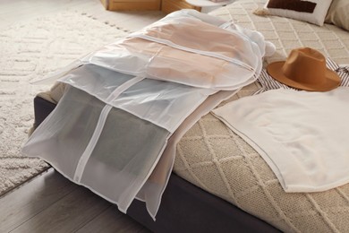 Photo of Garment covers with clothes on bed indoors