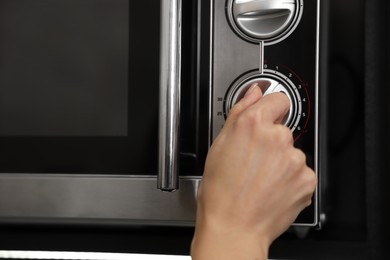 Woman turning on microwave at home, closeup