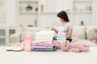 Baby's stuff on white table and mother packing bag, selective focus