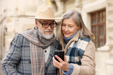 Photo of Lovely elderly couple with smartphone on city street