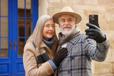 Happy elderly couple taking selfie on city street