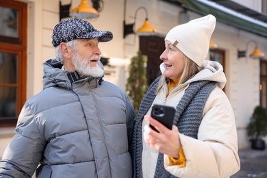 Photo of Happy elderly couple with smartphone on city street