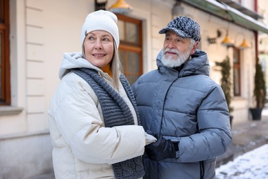 Happy elderly couple holding hands on city street