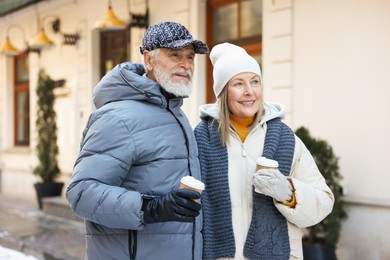 Photo of Happy elderly couple with paper cups on city street