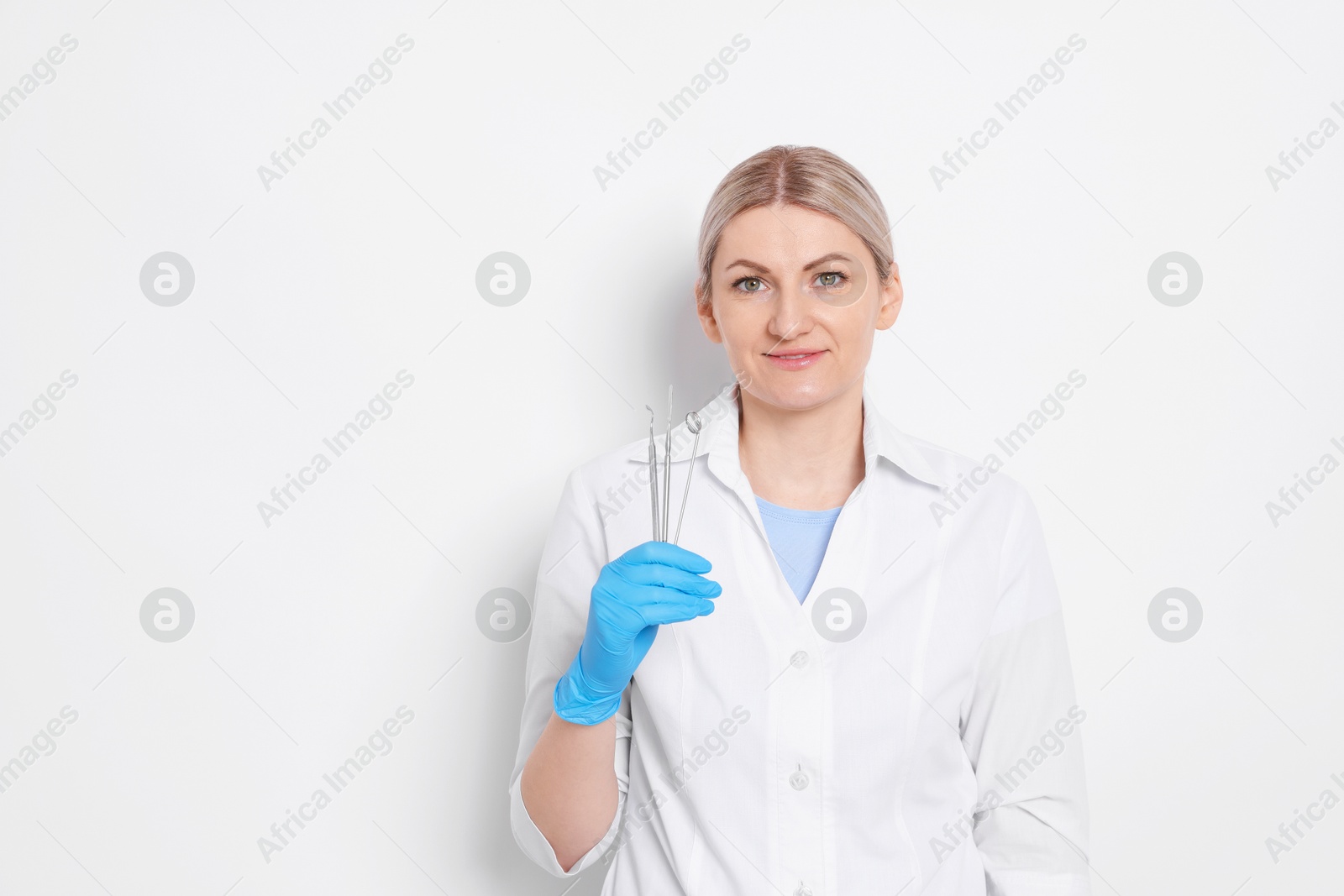 Photo of Professional dentist with tools on white background. Space for text