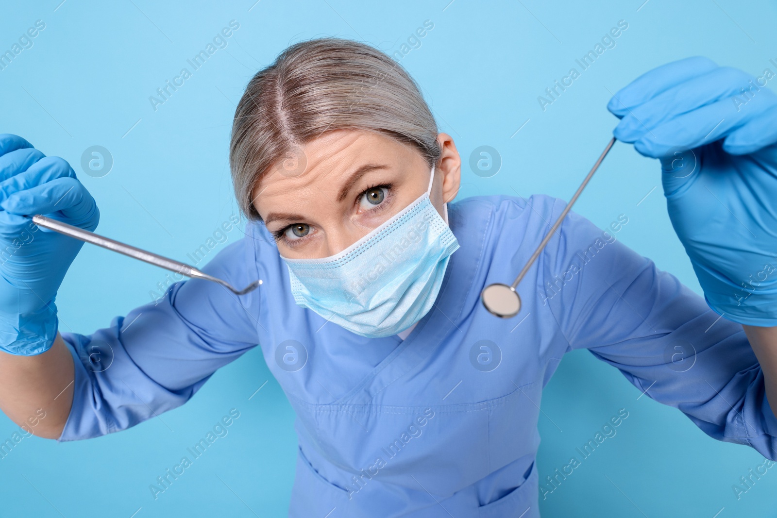 Photo of Professional dentist with tools on light blue background